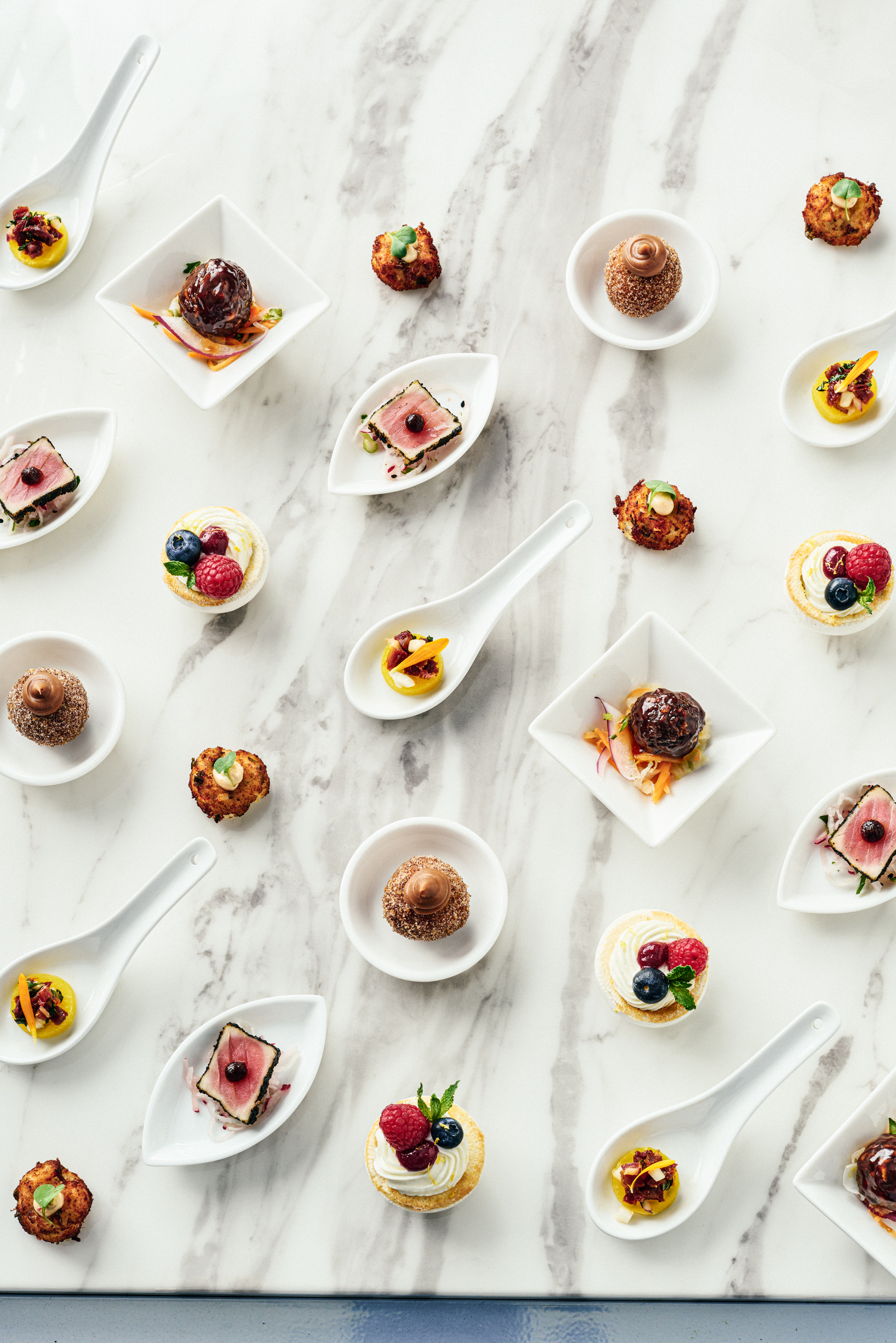 Various Hors d'Oeuvres served on different plates, bowls, and spoons.