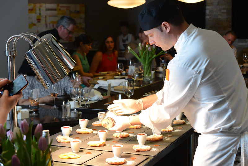 A cook prepares dishes in front of guests.