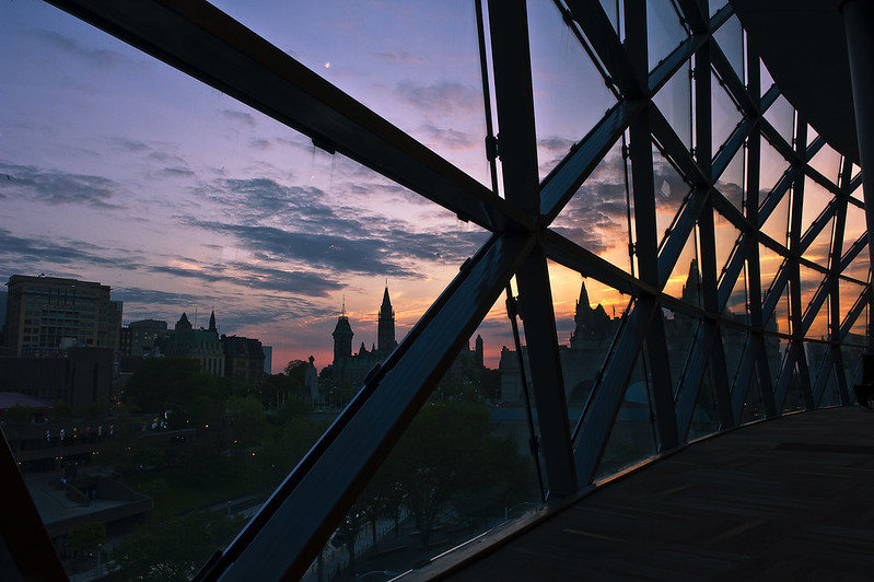 A view of the Parliament at sunset through the Shaw Centre's windows.